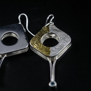 Contemporary dangle earrings with reticulated sterling silver, keum boo 24k gold foil and blue topaz, double-sided. On Black Background. One with the Front side UP and the Other with the Back Side Up.