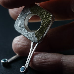 Contemporary dangle earrings with reticulated sterling silver, keum boo 24k gold foil and blue topaz, double-sided. In Hand.