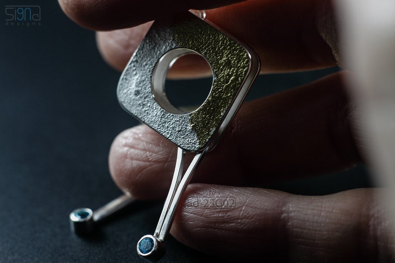 Contemporary dangle earrings with reticulated sterling silver, keum boo 24k gold foil and blue topaz, double-sided. In Hand.