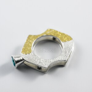 Contemporary ring with reticulated sterling silver and keum boo 24k gold foil and blue topaz stone, double-sided. On White Background.