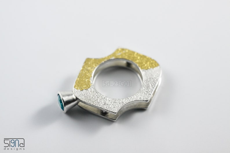 Contemporary ring with reticulated sterling silver and keum boo 24k gold foil and blue topaz stone, double-sided. On White Background.