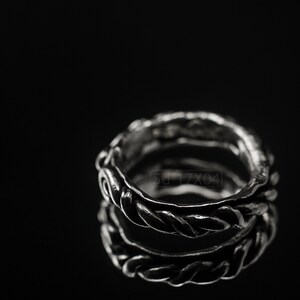 Primitive, raw, organic unisex sterling silver ring with twisted design and patina. On black background with mirror reflection from underneath.