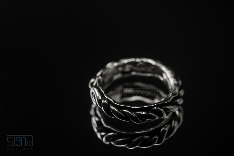 Primitive, raw, organic unisex sterling silver ring with twisted design and patina. On black background with mirror reflection from underneath.