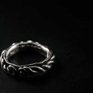 Primitive, raw, organic unisex sterling silver ring with twisted design and patina. On black background.