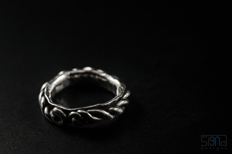 Primitive, raw, organic unisex sterling silver ring with twisted design and patina. On black background.