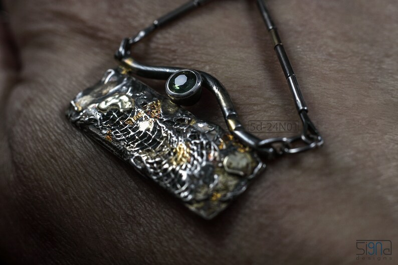 Mixed Metal Organic Necklace with Greenish Blue Sapphire and Topaz, Dark Texture, Statement Edgy Asymmetrical Chain, Silver and Gold Accents. On Hand Skin.