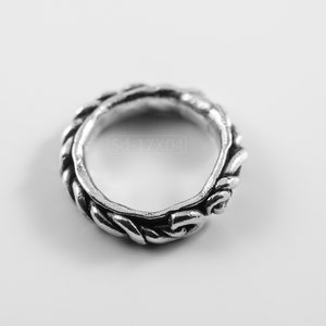 Primitive, raw, organic unisex sterling silver ring with twisted design and patina. On white background. Top view.