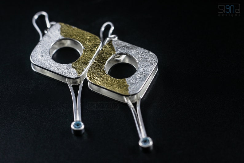 Contemporary dangle earrings with reticulated sterling silver, keum boo 24k gold foil and blue topaz, double-sided. On Black Background.