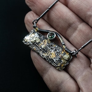 Mixed Metal Organic Necklace with Greenish Blue Sapphire and Topaz, Dark Texture, Statement Edgy Asymmetrical Chain, Silver and Gold Accents. On palm.