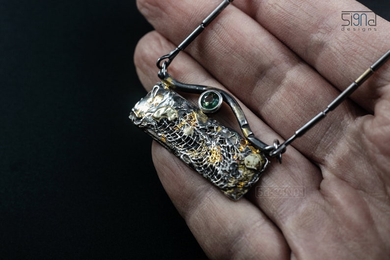 Mixed Metal Organic Necklace with Greenish Blue Sapphire and Topaz, Dark Texture, Statement Edgy Asymmetrical Chain, Silver and Gold Accents. On palm.