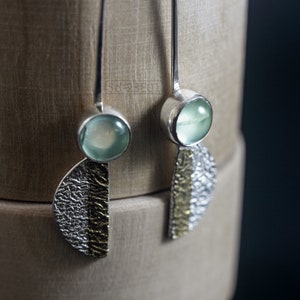 Reticulated Silver Earrings with 24k Keum-Boo Gold Foil and Prehnite Cabochons, Organic and Contemporary. Reticulated Half Oval Shape with a Stripe of Gold Leaf and Long Ear Wires. Hanging on wood.