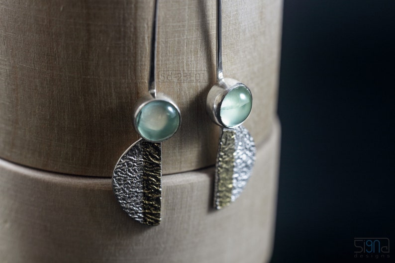 Reticulated Silver Earrings with 24k Keum-Boo Gold Foil and Prehnite Cabochons, Organic and Contemporary. Reticulated Half Oval Shape with a Stripe of Gold Leaf and Long Ear Wires. Hanging on wood.