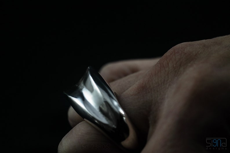 Geometric Ring, Contemporary Design, Massive, Bold and Unisex, with High Shine Finish. On finger, black background.