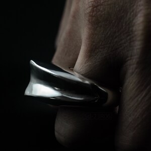 Geometric Ring, Contemporary Design, Massive, Bold and Unisex, with High Shine Finish. On finger, black background. Side view.