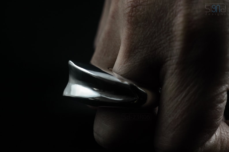 Geometric Ring, Contemporary Design, Massive, Bold and Unisex, with High Shine Finish. On finger, black background. Side view.