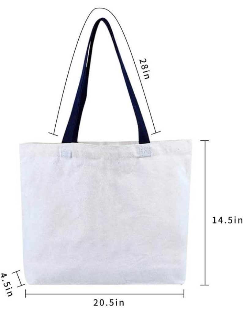 May include: White canvas tote bag with navy blue handles. The bag measures 20.5 inches wide, 14.5 inches tall, and has a handle drop of 28 inches.