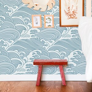 May include: A blue and white wave pattern wallpaper with a wooden mirror, two framed pictures, and a red wooden stool in front of it.