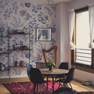 May include: A dining room with a floral wallpaper, a harp, a table with four chairs, and a bookshelf. The table is made of wood and has a round top. The chairs are black and have a wooden frame. The bookshelf is made of metal and has four shelves. The harp is made of wood and has a gold finish.