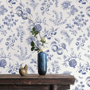May include: A white background with a blue floral pattern featuring pomegranates, apples, berries, and roses. A wooden table with a blue vase and a gold bird figurine.