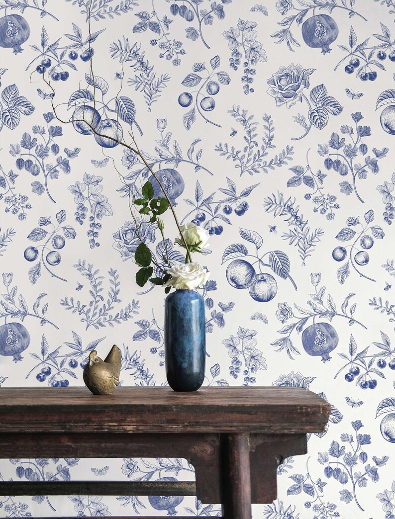 May include: A white background with a blue floral pattern featuring pomegranates, apples, berries, and roses. A wooden table with a blue vase and a gold bird figurine.