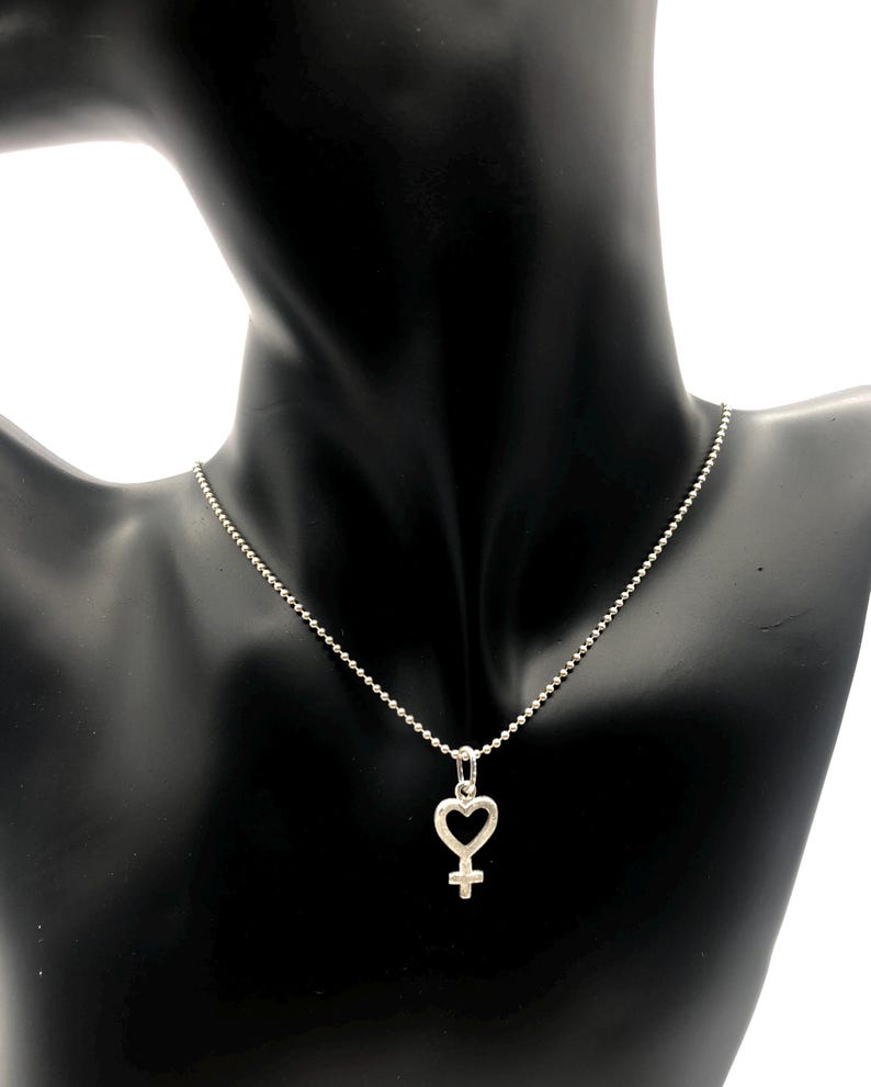 May include: A silver necklace with a heart-shaped pendant featuring the female symbol.