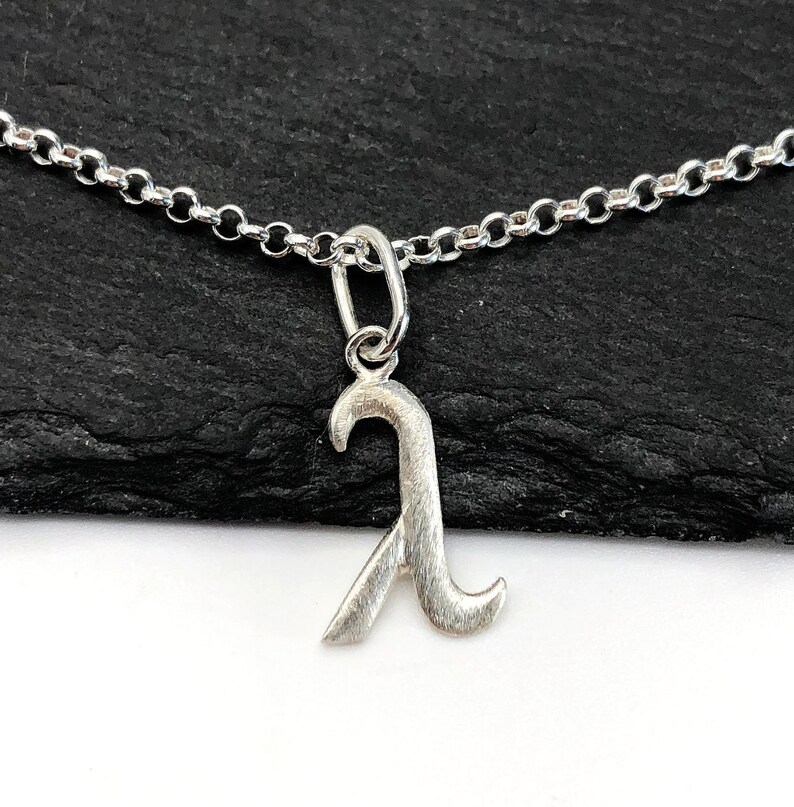 K&ouml;nnte beinhalten: Eine silberne Halskette mit einem stilisierten '&lambda;'-Anh&auml;nger.