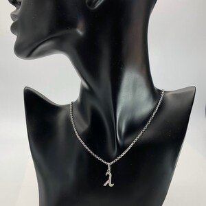 K&ouml;nnte beinhalten: Eine silberne Kettenkette mit einem silbernen Anh&auml;nger in Form des Buchstabens 'A'.