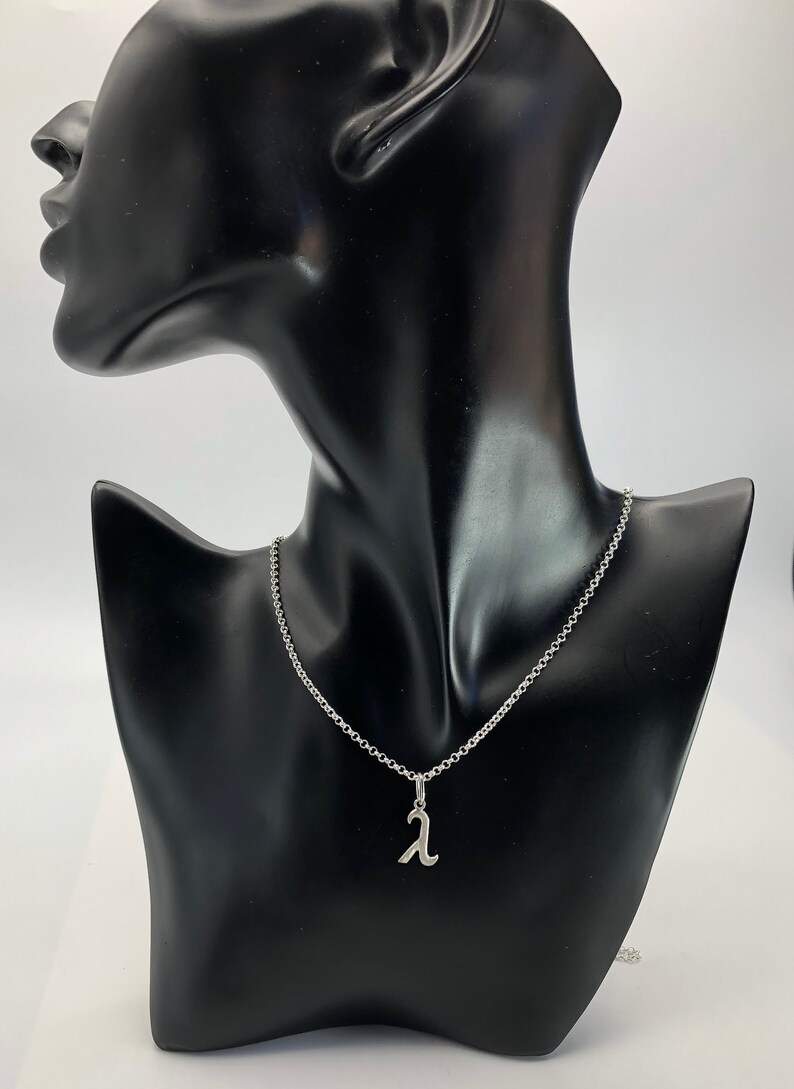 K&ouml;nnte beinhalten: Eine silberne Kettenkette mit einem silbernen Anh&auml;nger in Form des Buchstabens 'A'.