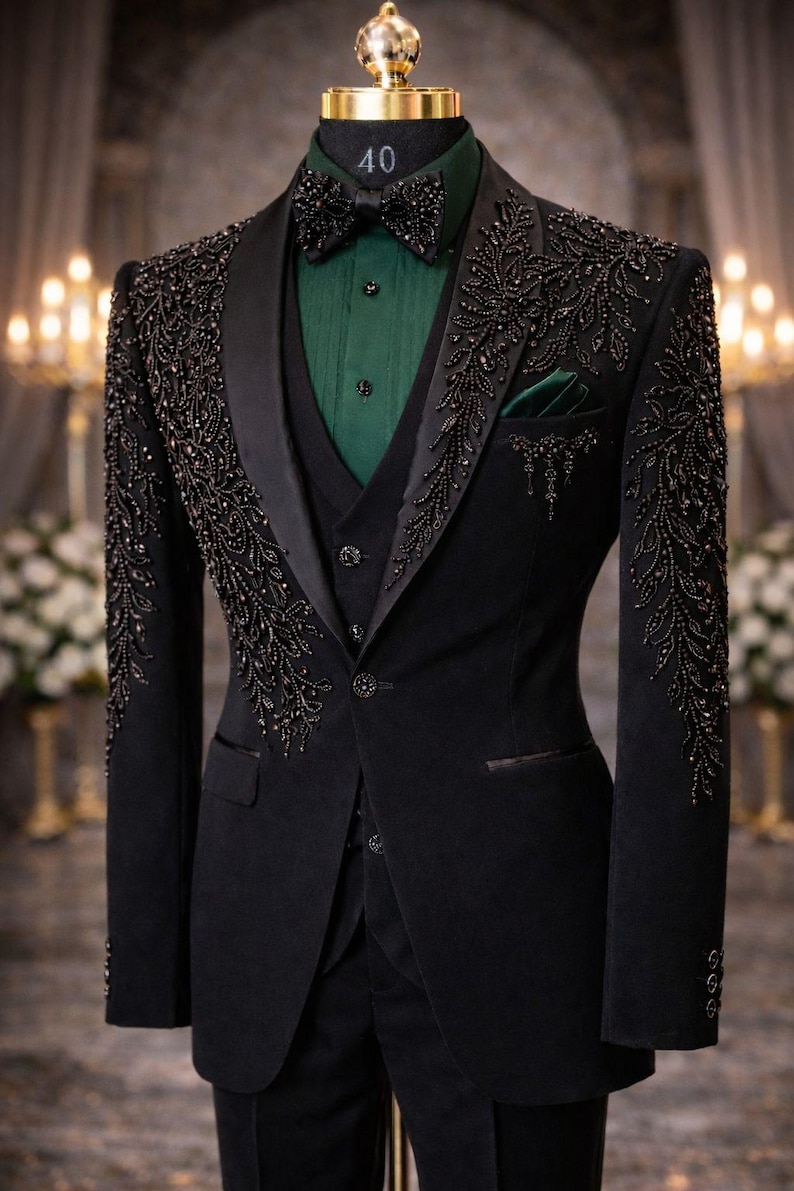 Peut inclure: Un costume noir formel avec des ornements de perles complexes sur les revers et les manches. Le costume comprend un gilet assorti, une chemise verte et un n&oelig;ud papillon. Une pochette verte ajoute une touche de couleur.