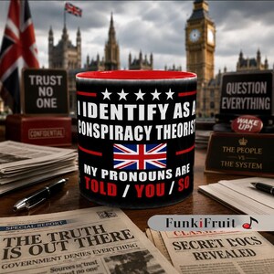 May include: A black mug with a red interior, emblazoned with the words "I Identify As A Conspiracy Theorist" and a Union Jack. The background includes newspapers, pens, and the Houses of Parliament.