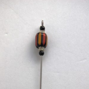 Puede incluir: Primer plano de una cuenta rayada de color negro y naranja con detalles plateados en un alambre plateado.