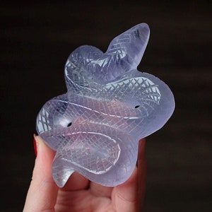 May include: A translucent purple glass sculpture of a snake with a detailed, textured surface.