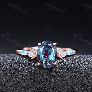 以下が含まれることがあります： 三日月形のオパールアクセントが2つ付いた、楕円形のアレキサンドライト宝石を備えたローズゴールドのリングです。