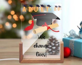 Adult Ed - We Change Lives Rectangular Acrylic Sign - Wooden Base