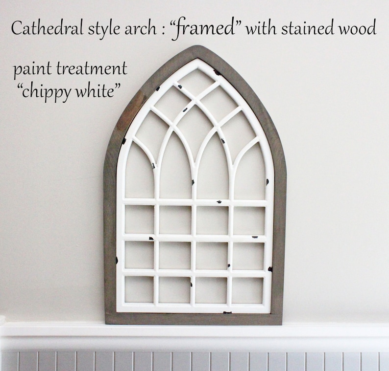 Pu&ograve; includere: Una cornice per finestra ad arco di cattedrale bianca con un bordo in legno tinto. La cornice &egrave; dipinta con una finitura "bianco scrostato", che le conferisce un aspetto invecchiato.