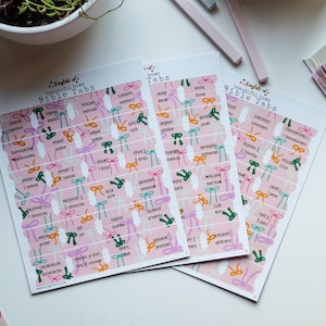 May include: A set of pink Bible tabs with colorful bows and the names of books of the Bible printed on them. The text "Engraved is beautiful bows Bible Tabs" is printed on the top of the sheets.