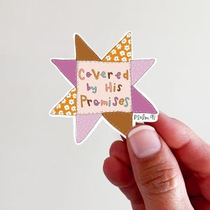 May include: A sticker in a starburst shape with the text "Covered by His Promises." The sticker has a patchwork design with brown, orange, and pink sections. The text is in a whimsical font, and the sticker includes the reference "Psalm 91."