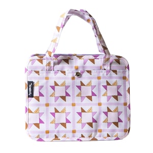 May include: A quilted tote bag with a star pattern in shades of purple, brown, and gold on a white background. The bag has a handle, a front pocket, and a snap closure. The label on the bag reads "?Work".