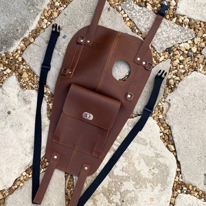 Puede incluir: Bolsa de dep&oacute;sito de motocicleta de cuero marr&oacute;n con cierre de solapa y dos correas ajustables. La bolsa tiene un peque&ntilde;o bolsillo en la parte delantera con una hebilla de metal.