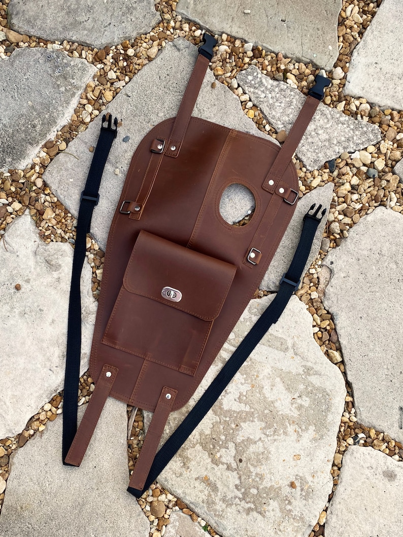 Puede incluir: Bolsa de dep&oacute;sito de motocicleta de cuero marr&oacute;n con cierre de solapa y dos correas ajustables. La bolsa tiene un peque&ntilde;o bolsillo en la parte delantera con una hebilla de metal.