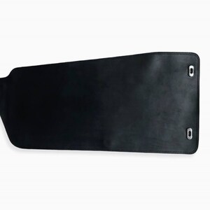 May include: Black leather flap with two silver metal grommets on the right side and one on the left side.