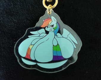 Op de afbeelding: Een heldere acryl sleutelhanger met een cartoon pony met een regenboog manen en staart, en regenboog vleugels. De pony is lichtblauw met een glimlachende uitdrukking. De sleutelhanger heeft een goudkleurige stervormige sluiting.