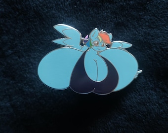 Op de afbeelding: Een lichtblauwe emaille pin met een cartoon pony met een regenboogmanen en -staart. De pony draagt een donkerblauwe badpak. De pin heeft een zilveren rand en staat tegen een donkerblauwe achtergrond.