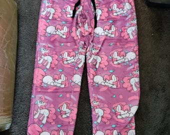 May include: Pink pajama pants with a repeating pattern of a pink pony with a blue mane and tail. The pants have a black drawstring.