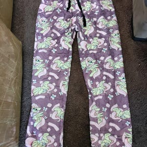 May include: Purple pyjama trousers with a repeating pattern of a pink pony with green wings and butterflies.