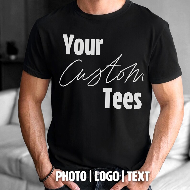 May include: Black t-shirt with the text "Your Custom Tees" in white. The shirt also has the text "PHOTO | LOGO | TEXT" at the bottom. The shirt is short-sleeved and appears to be made of a soft material.