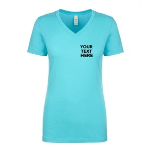 May include: A bright turquoise short-sleeve t-shirt with a V-neckline. The front of the shirt features the black text "YOUR TEXT HERE" printed on the upper left chest area. The garment has a standard fit with a straight hemline and a white neck label.