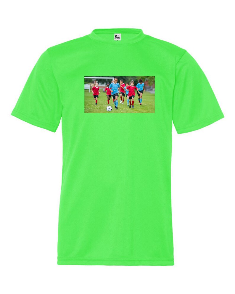 May include: A bright green t-shirt with a picture of a group of children playing soccer on the front. The children are wearing blue and red jerseys and are running with a soccer ball.