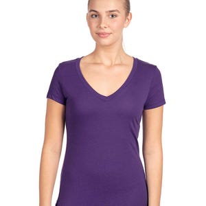 May include: A solid deep purple short-sleeved t-shirt featuring a V-neckline. The garment is constructed with a fitted silhouette, short sleeves, and a straight hemline, providing a clean and simple look in a vibrant, saturated purple color.