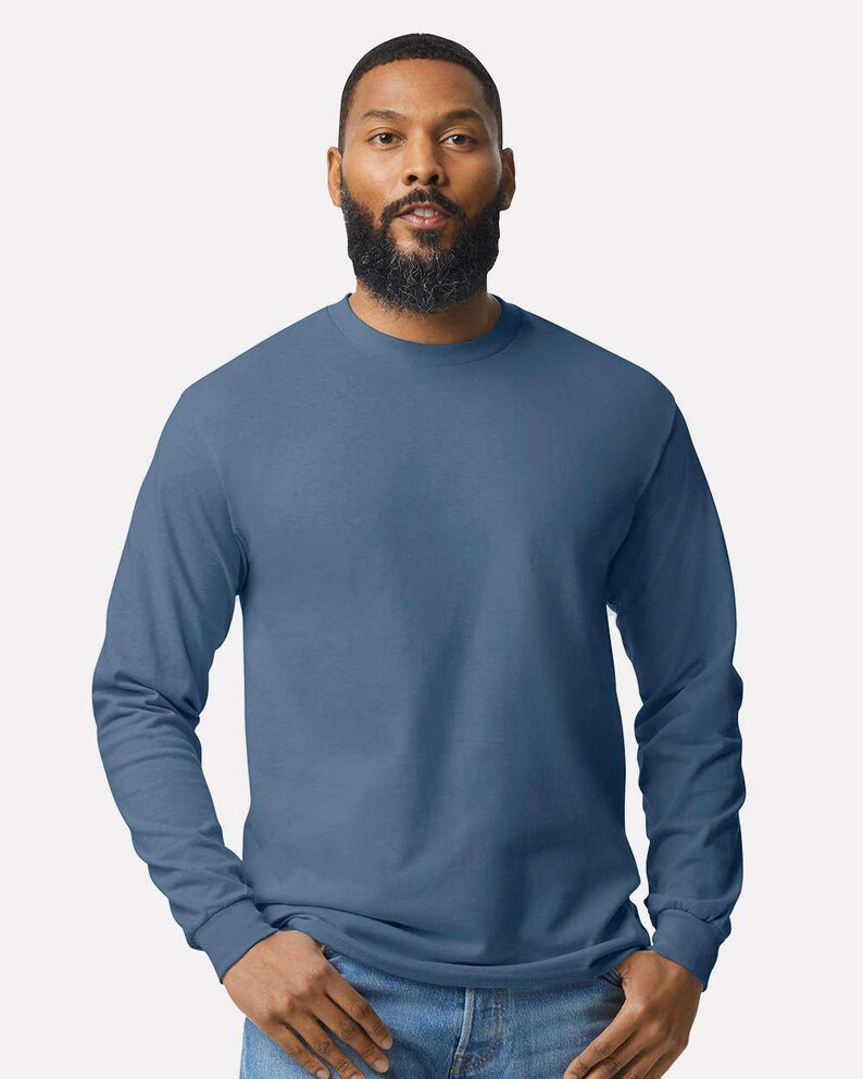 May include: A solid slate blue long-sleeve crew neck t-shirt made of a smooth fabric. The shirt features a standard fit with long sleeves that end in ribbed cuffs and a classic round neckline, providing a simple and clean appearance for daily wear.
